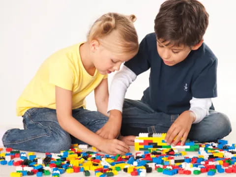a boy and girl playing with a puzzle