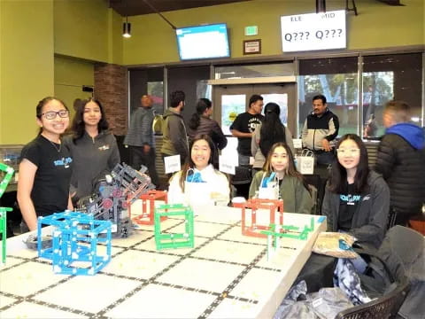 a group of people posing for a photo with a table of toys