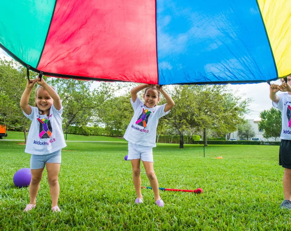 a group of kids holding a large colorful kite