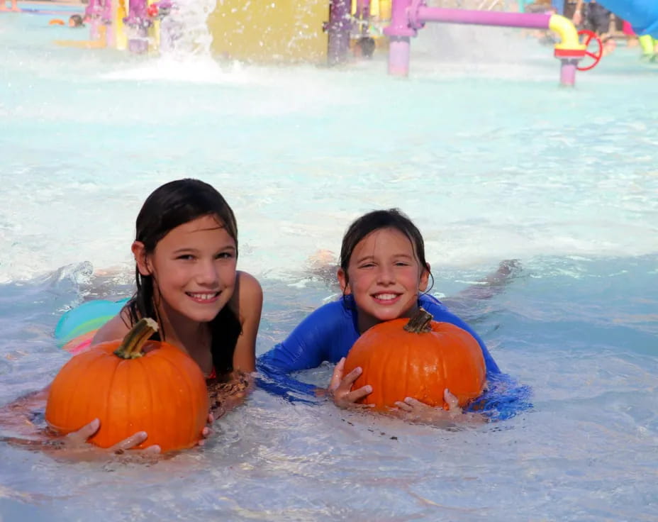 a couple of women in a pool with pumpkins