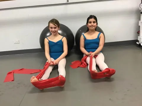 two women sitting on red and black mats