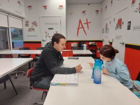 a man and a woman sitting at a table looking at a paper