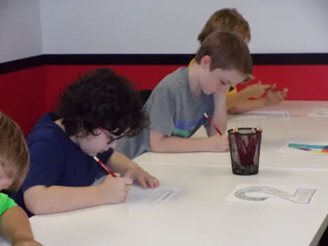 a group of children sitting at a table writing on paper
