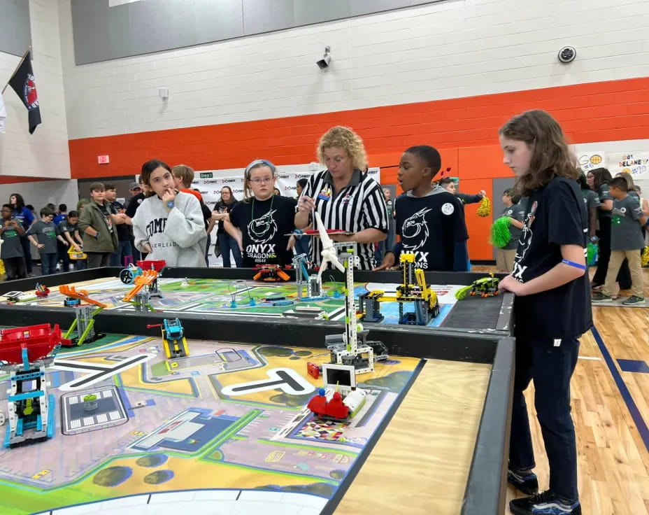 a group of people standing around a table with a model train on it