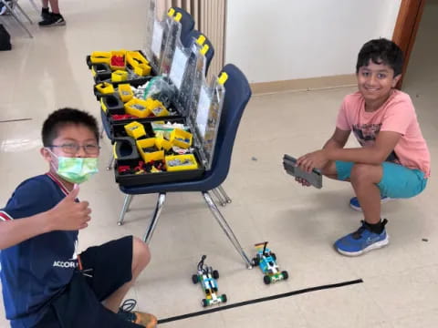 two boys sitting on the floor next to a shopping cart with toys