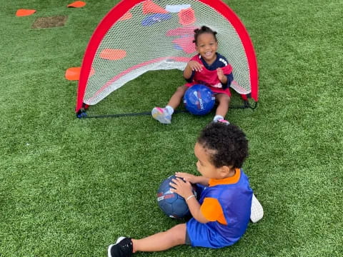 a couple of kids playing with a ball in a grassy area