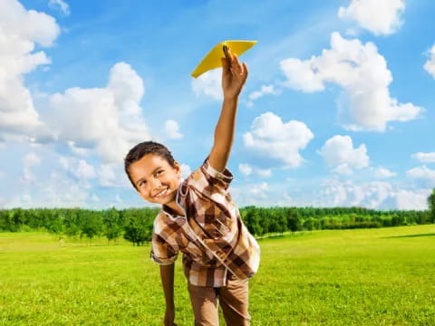 a boy holding a yellow frisbee in a field