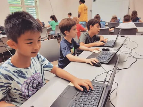 a group of children using laptops