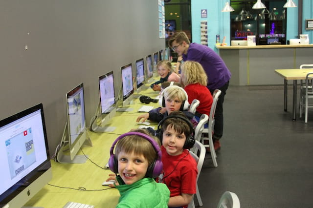 a group of children sitting at desks in a room with computers