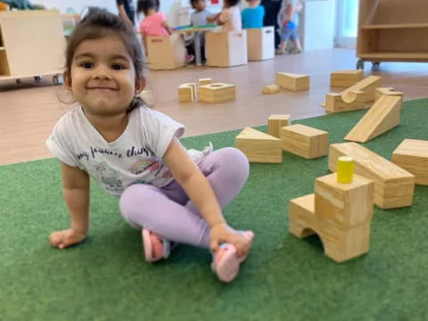 a girl sitting on the floor with wooden blocks