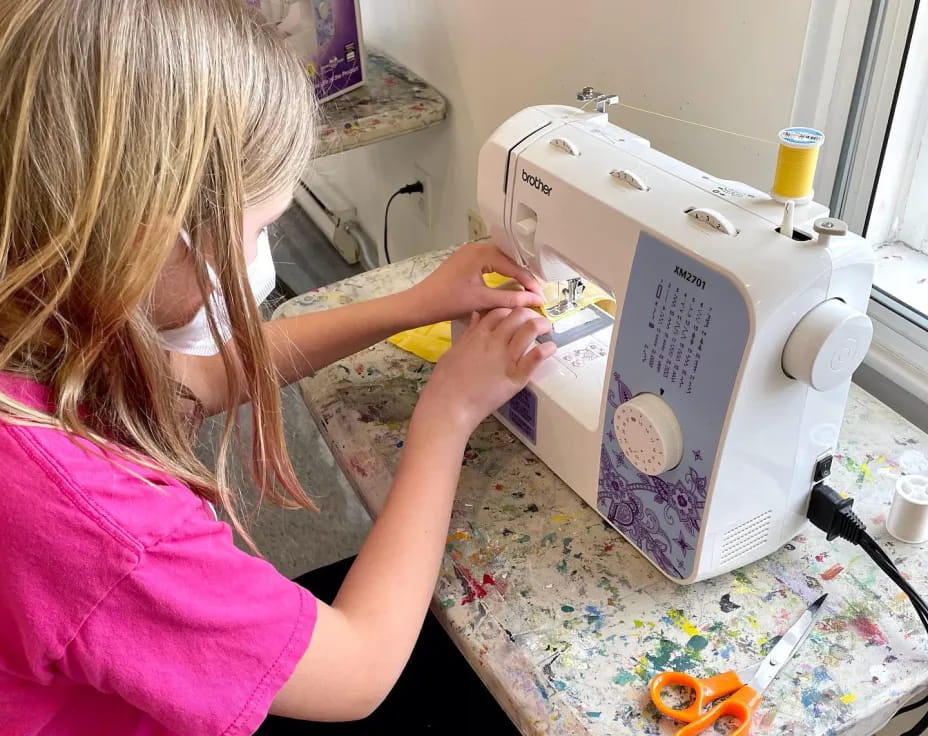 a young girl using a sewing machine