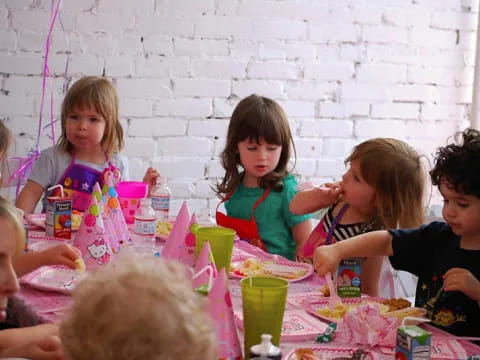 a group of children sitting around a table with colorful cups