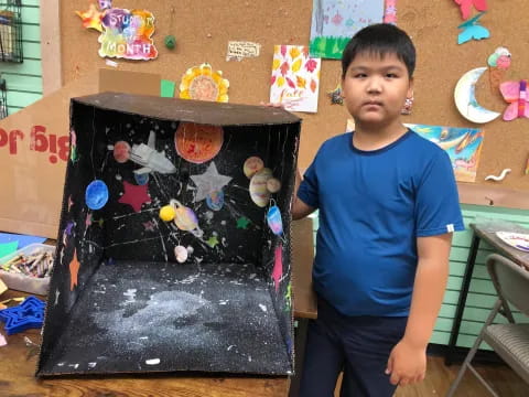 a boy standing next to a painting