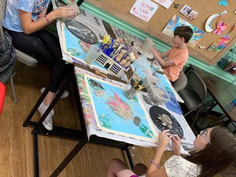 a group of people sitting around a table with a painting on it
