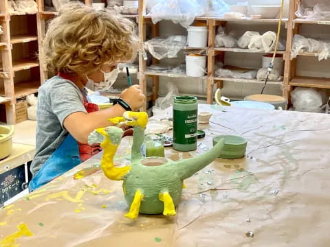 a person painting a green dinosaur