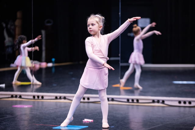 a girl in a pink dress dancing on a stage