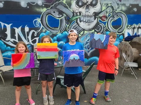 a group of children posing for a photo in front of a mural