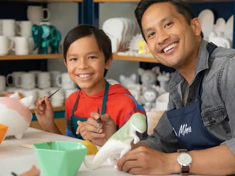 a person and a boy sitting at a table with a book and a bowl of food