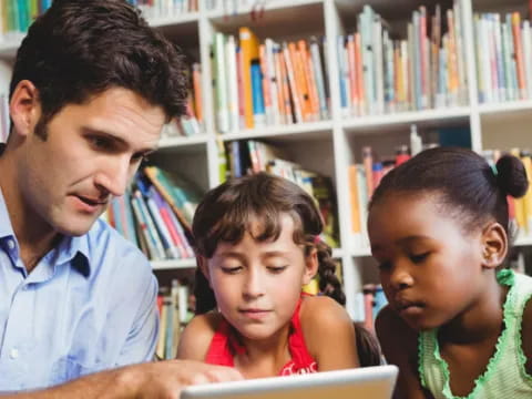 a man and a couple of children looking at a tablet