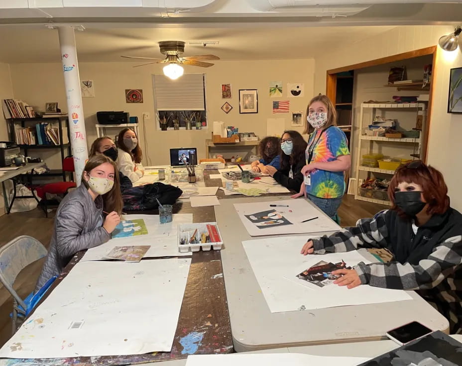 a group of people sitting at a table with masks on