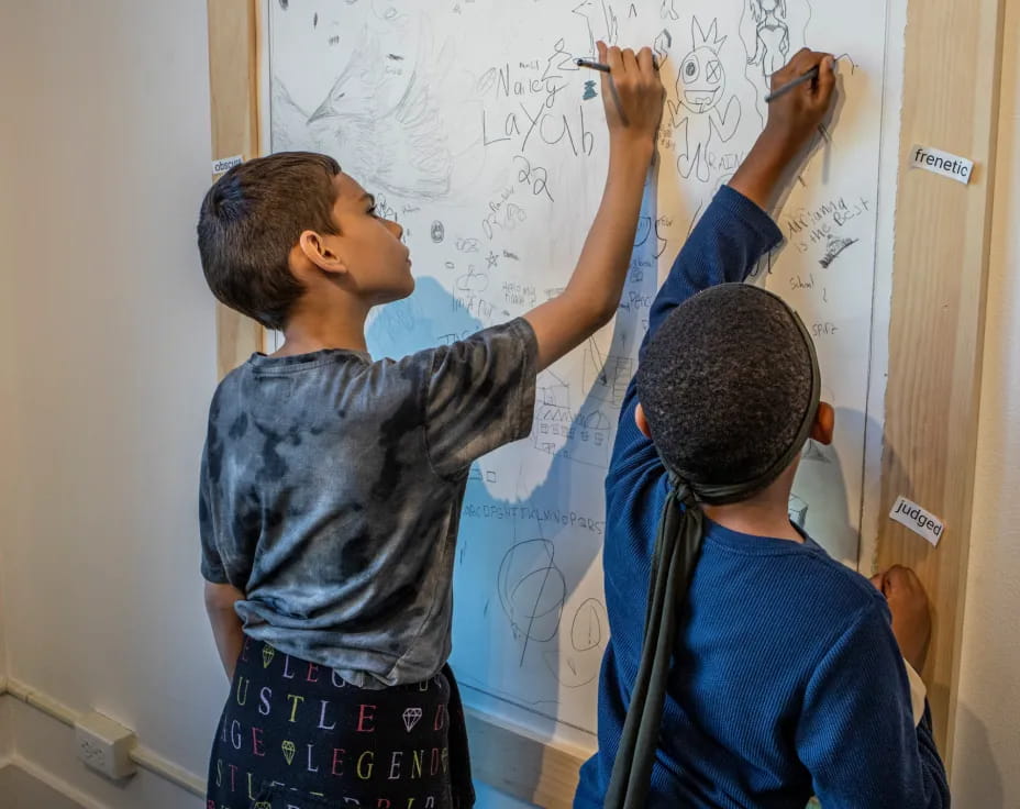 a few boys writing on a white board