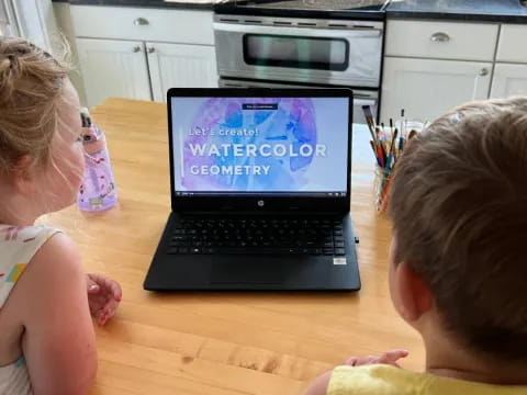a couple of kids looking at a laptop