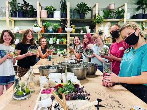 a group of people sitting at a table with plants and drinks