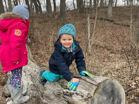 a couple of children on a tree stump in the woods