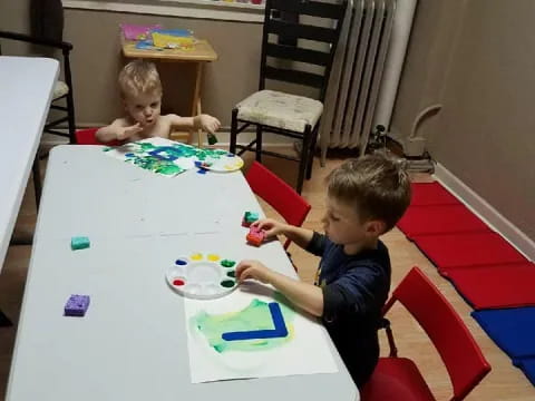 a couple of kids sitting at a table with a toy