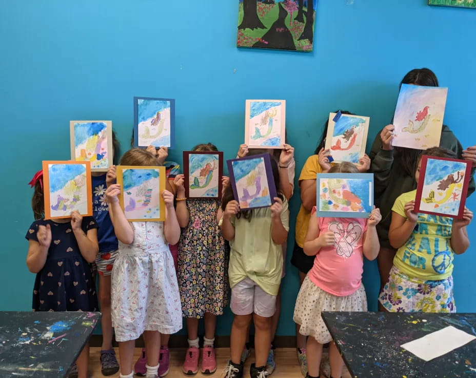 a group of children holding up framed pictures