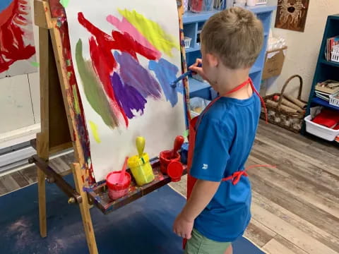 a boy painting on a easel