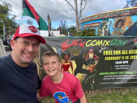 a man and a boy posing in front of a sign