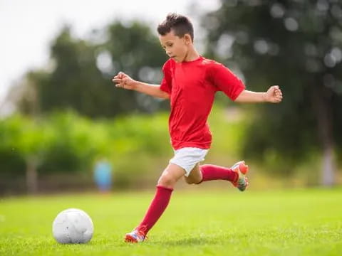 a boy kicking a football ball