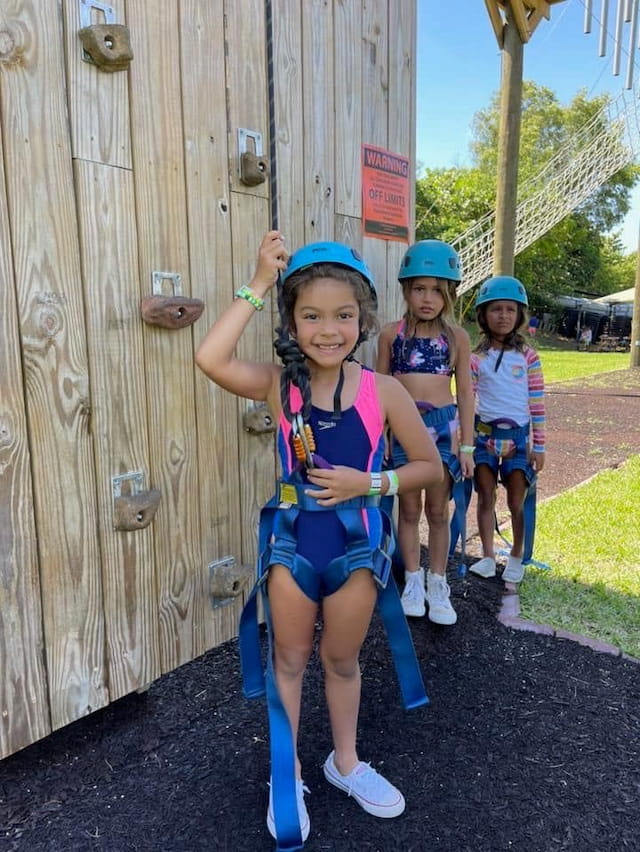 a group of kids wearing helmets and standing next to a wooden fence