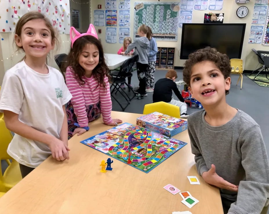 a group of children sitting at a table with a board game