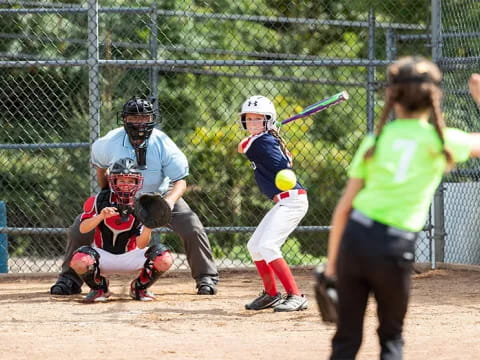 a girl hitting a ball with a baseball bat