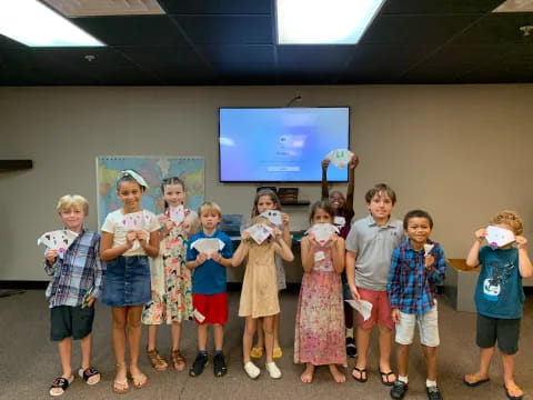 a group of children posing for a photo in front of a projector screen