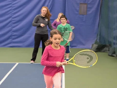 a little girl holding a tennis racket