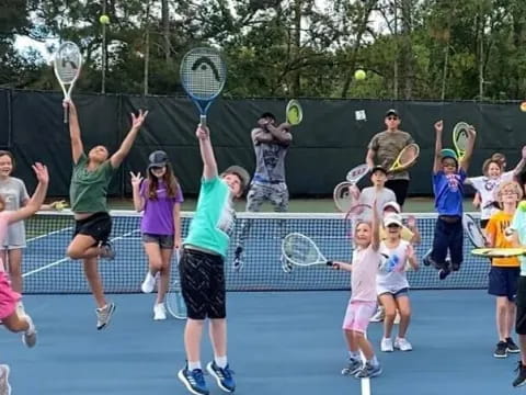 a group of kids playing tennis