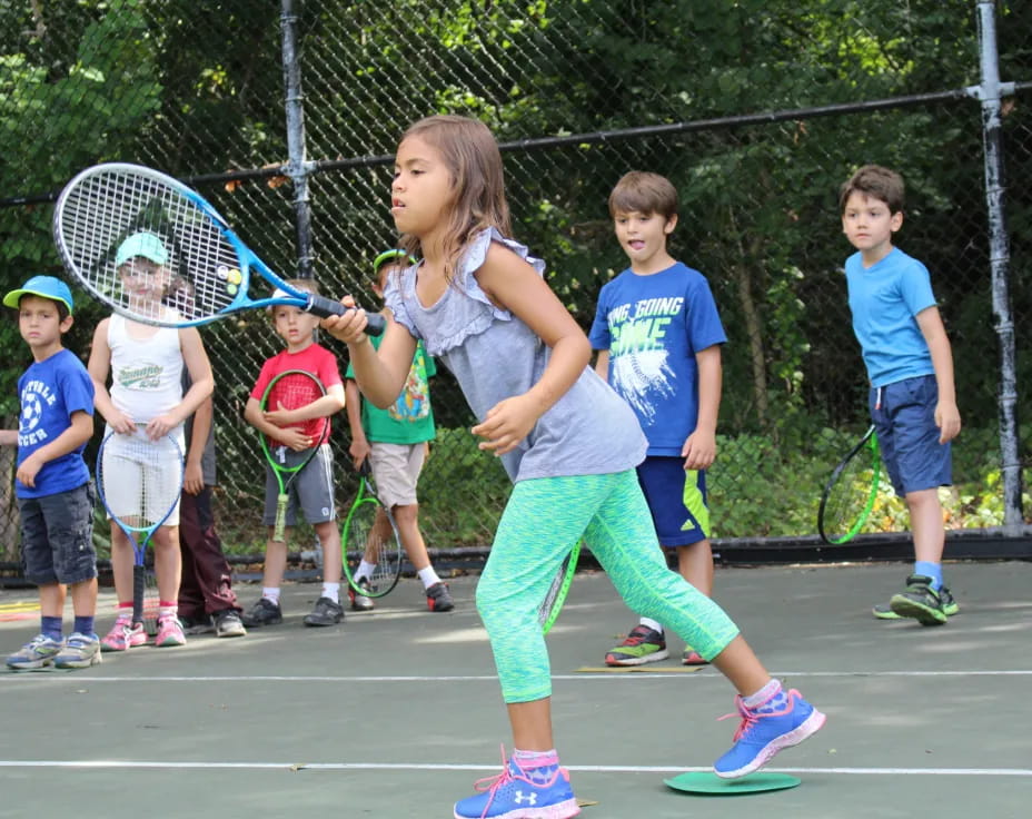 a group of kids playing tennis