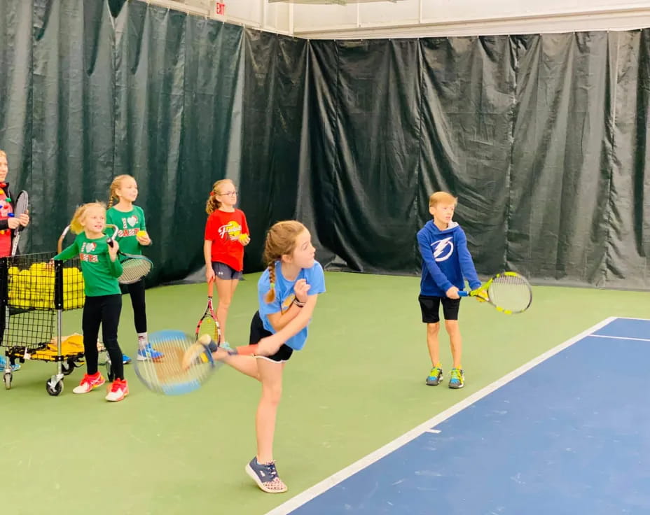 a group of kids playing tennis