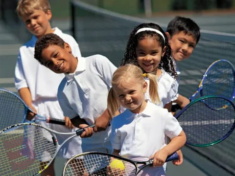 a group of kids playing tennis