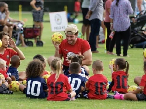 a group of kids sitting on the grass with some holding balls