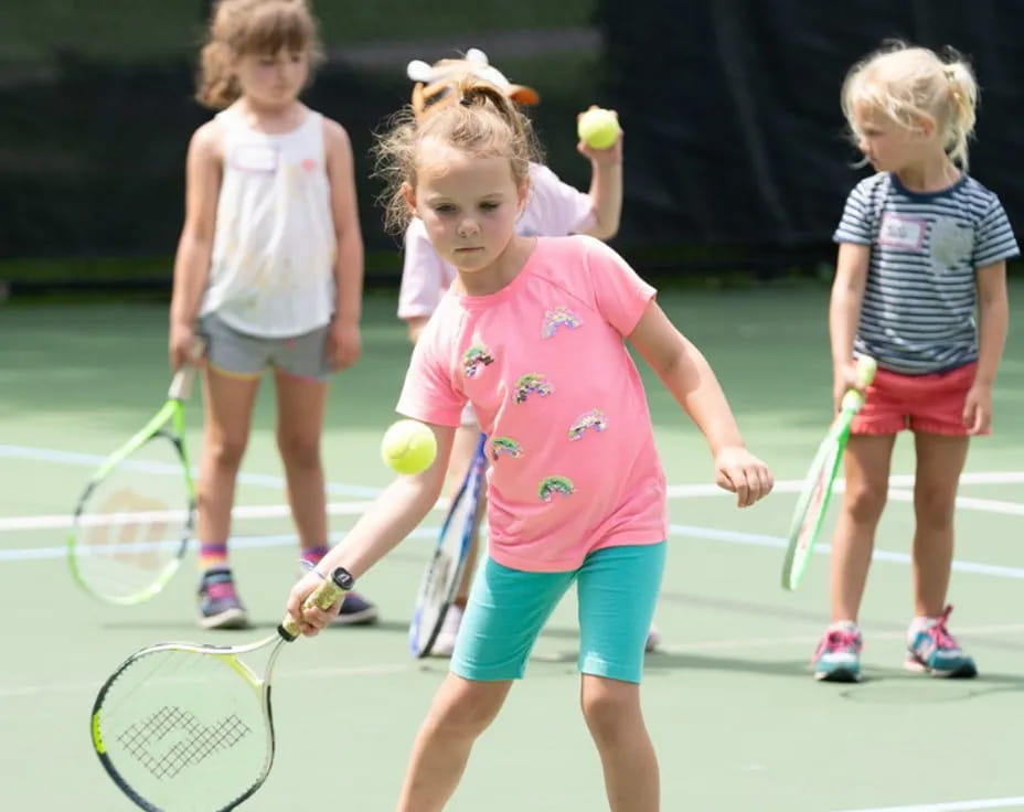 a group of kids playing tennis