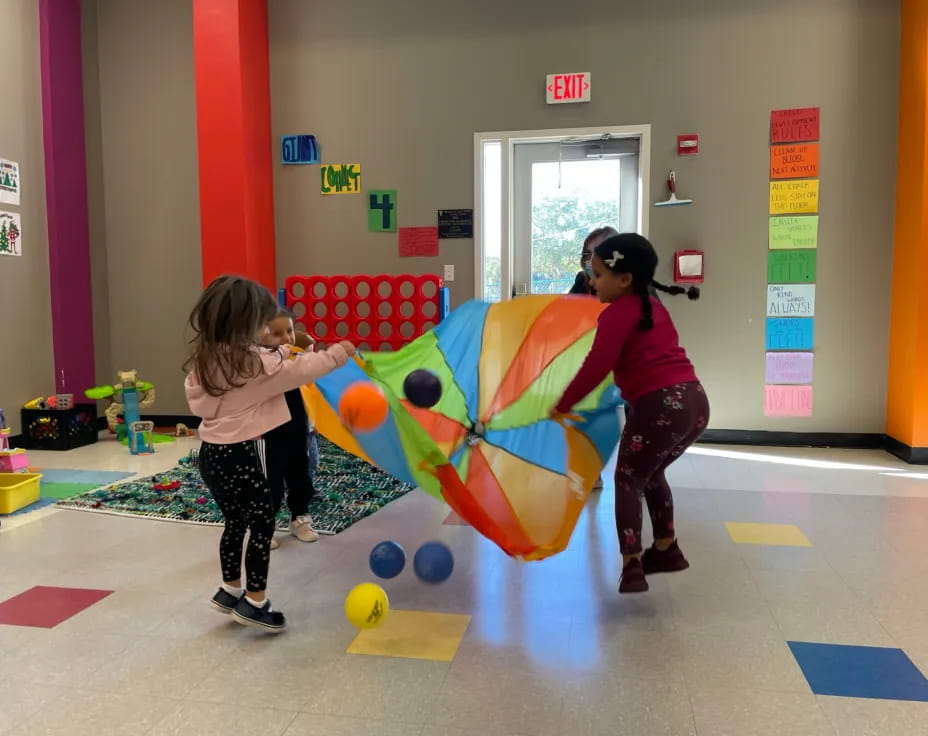 a person and a girl playing with a large ball in a gym