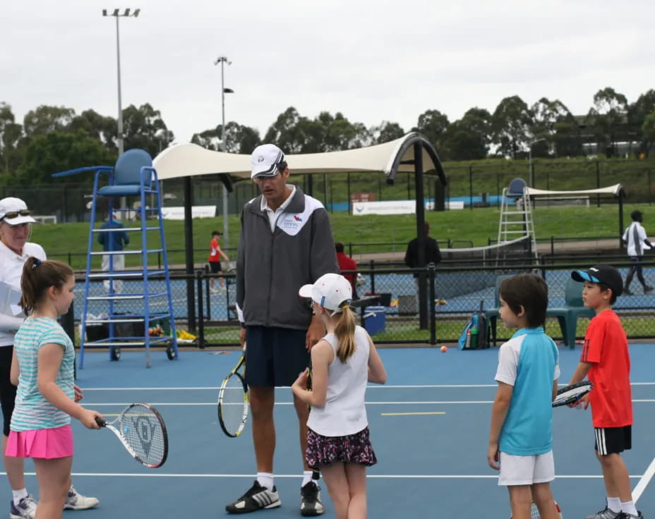 a group of kids playing tennis