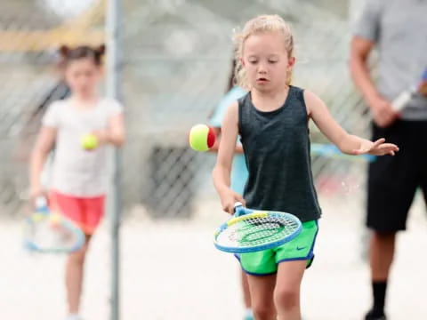a little girl playing tennis
