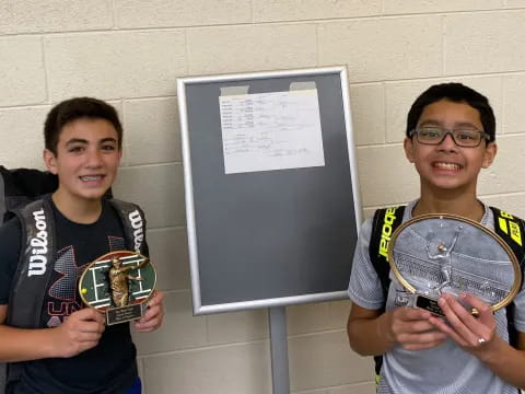 a couple of boys holding a trophy