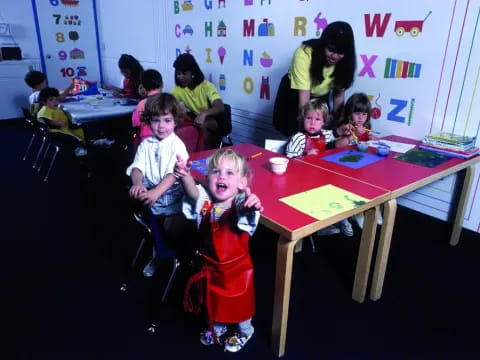 a group of children sitting at a table in a classroom