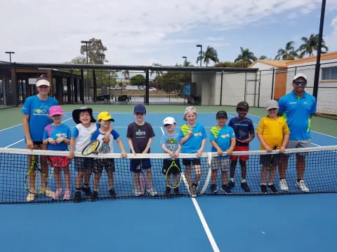 a group of people posing for a photo on a tennis court